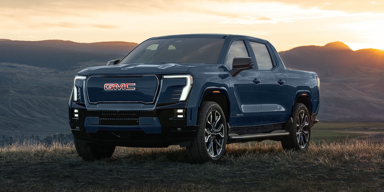 Vue latérale avant du pick-up Sierra EV 2026 stationné dans un pré.