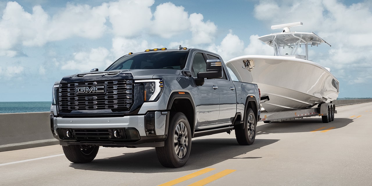 Le pick-up GMC Sierra HD 2026 qui tire une remorque sur la route.