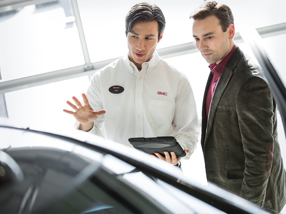 Image of two men discussing a vehicle at a GMC Business Elite Dealer.