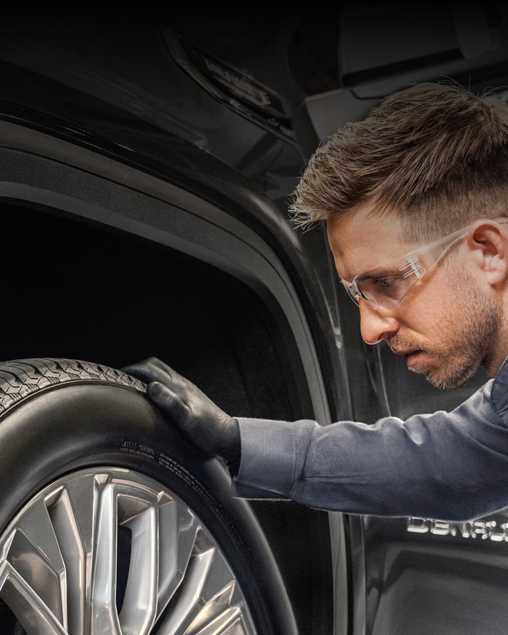A Mechanic Is Wearing Goggles and Inspecting a Tire