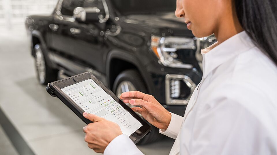 GMC Representative Holding a Tablet Standing Next to a GMC Truck
