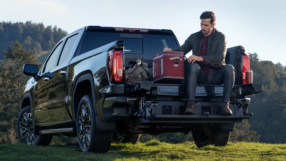 Man sitting on the tailgate of a 2023 Sierra 1500 Denali Ultimate.