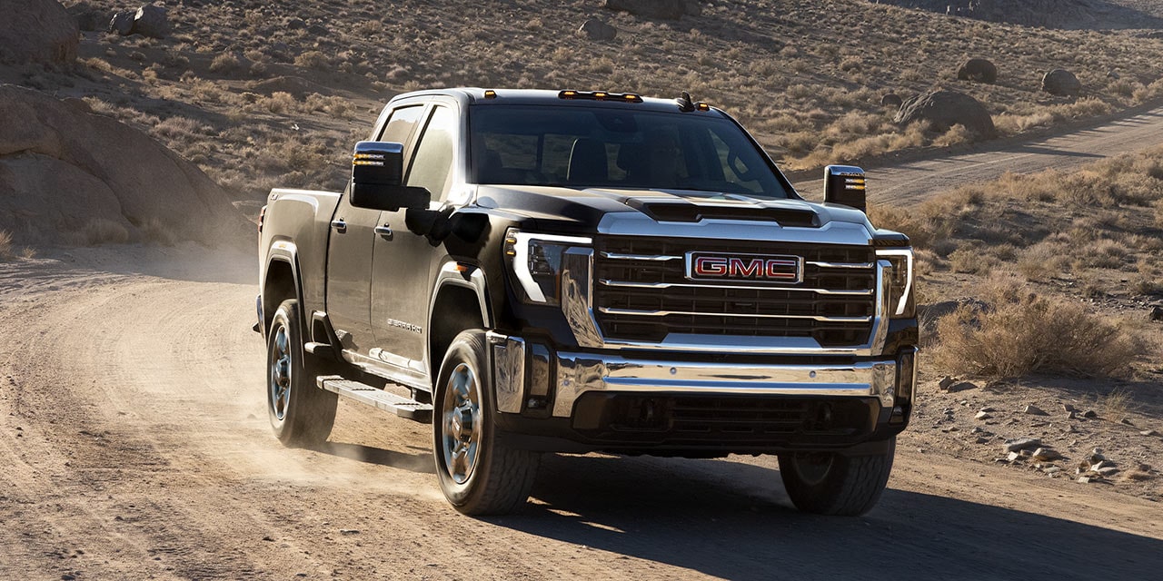 Front Three-Quarter View of the 2026 GMC Sierra Chassis Cab Work Truck Driving Down a Dirt Road