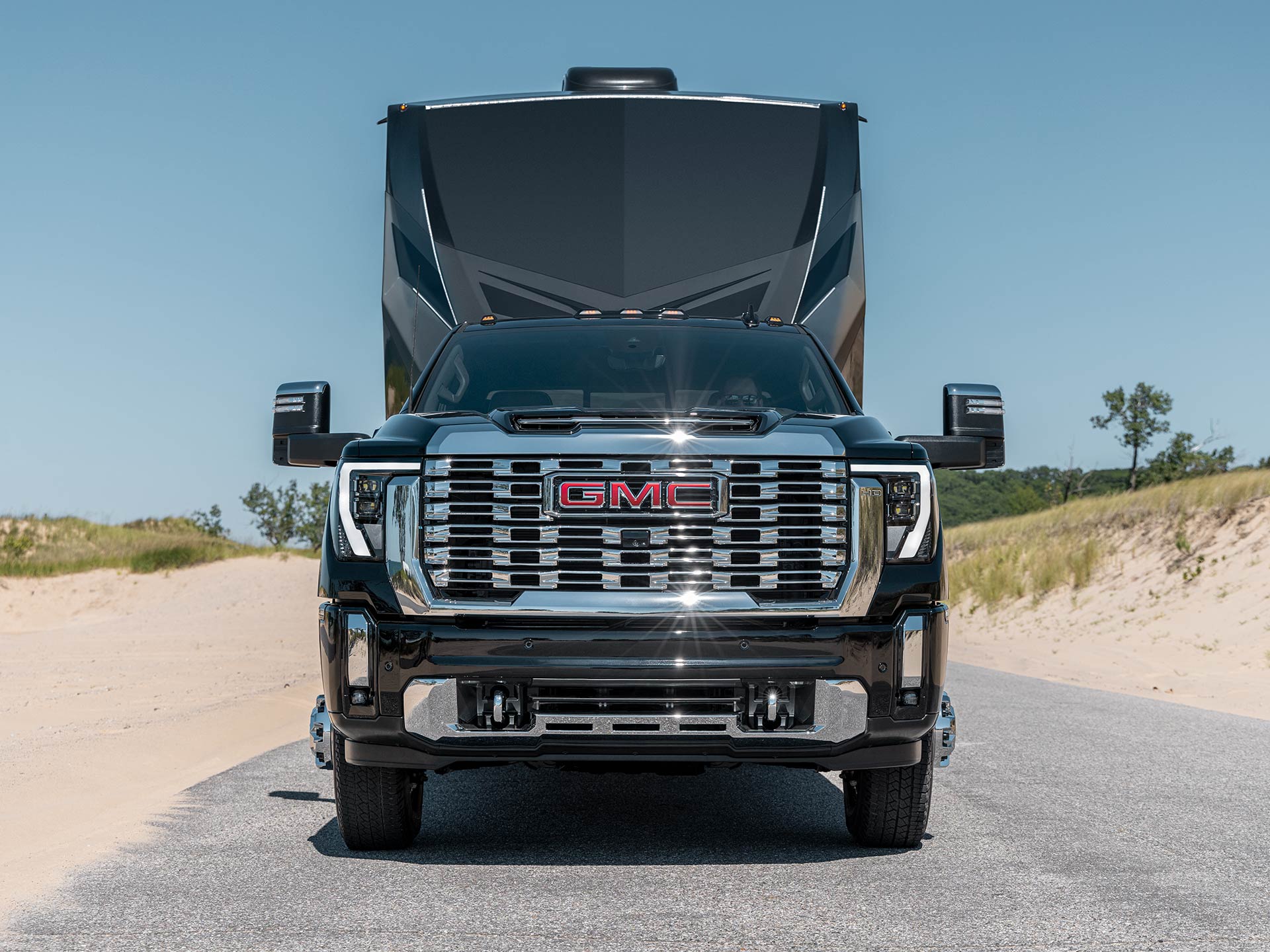 Front View of the Bold 2026 GMC Sierra HD Hauling a RV on a Sandy Road